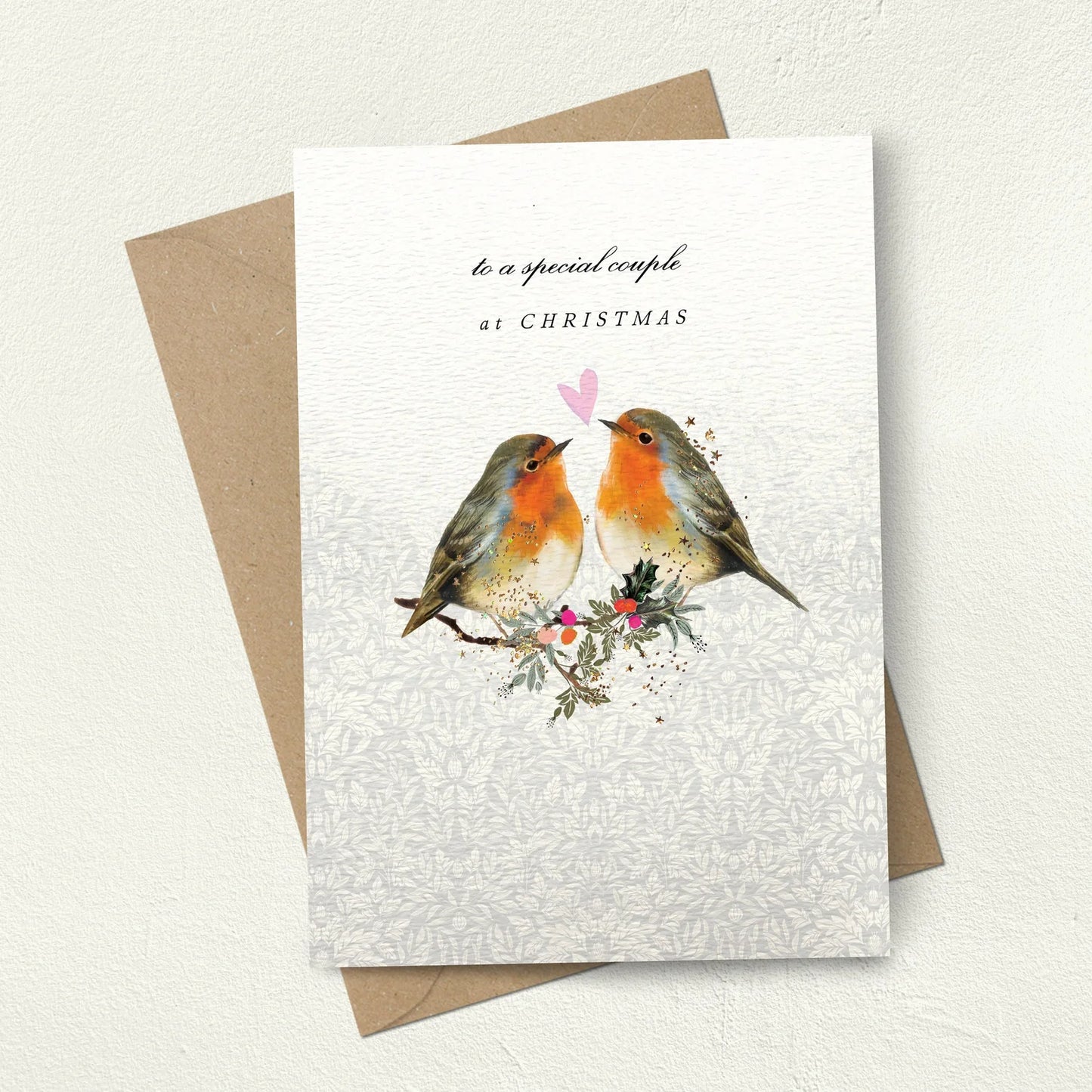 Greeting card with two robins and a pink heart, featuring a brown envelope on a light background.