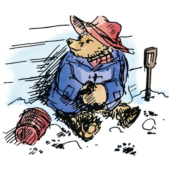 paddington bear in a blue outfit and red hat sitting in the snow with a spade and ball of yarn.
