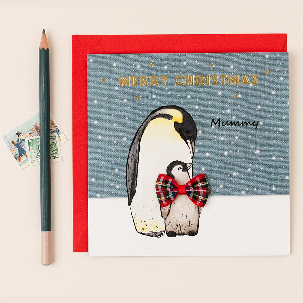 Christmas card with penguins and a red envelope on a light beige background
