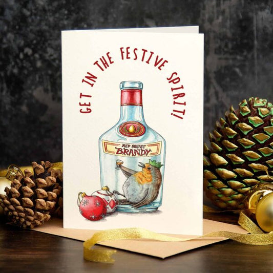 Greeting card with brandy bottle illustration and festive text, surrounded by pine cones and a gold ribbon.