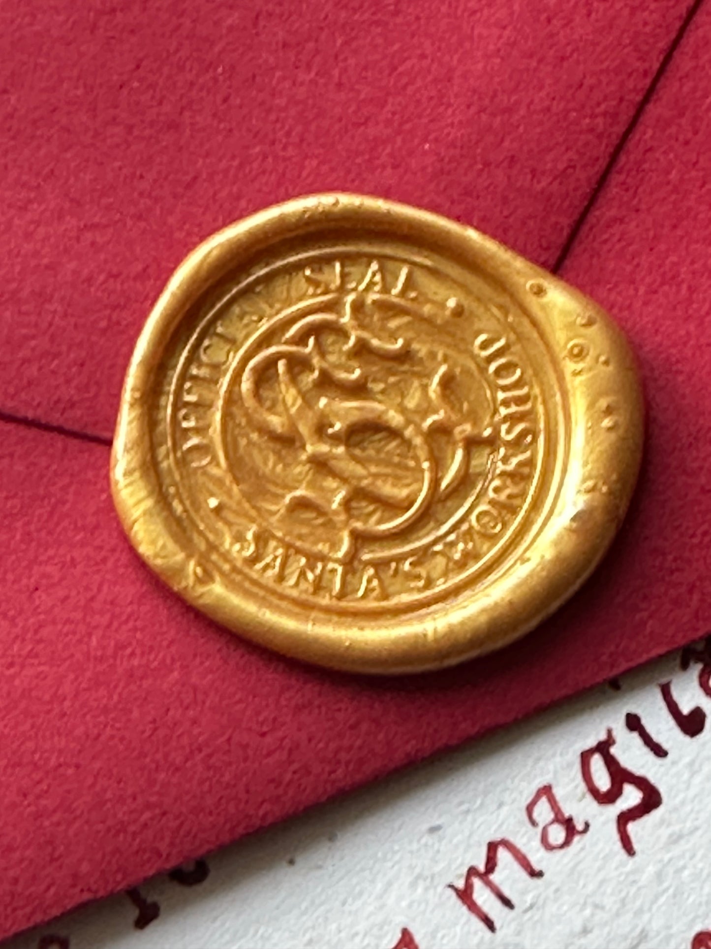 Gold wax seal stamped with Santa’s mark on red envelope — luxury Christmas letter detail.