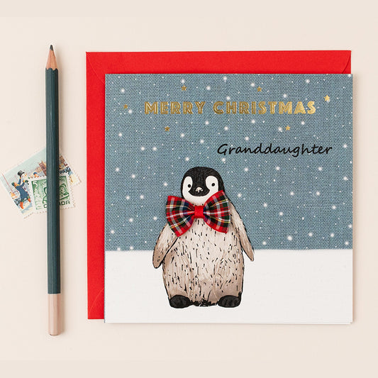 Christmas card with a penguin wearing a bow tie, addressed to a granddaughter, on a beige background.